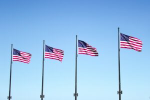 four USA flags under blue sky