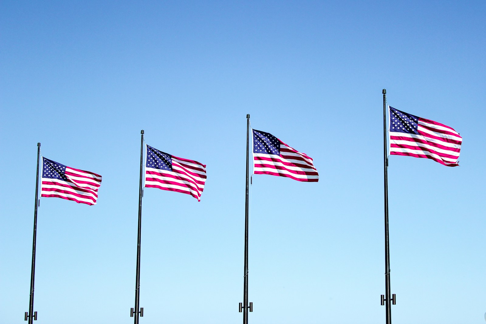 four USA flags under blue sky