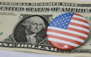 a one dollar bill and a button with a picture of george washington on it