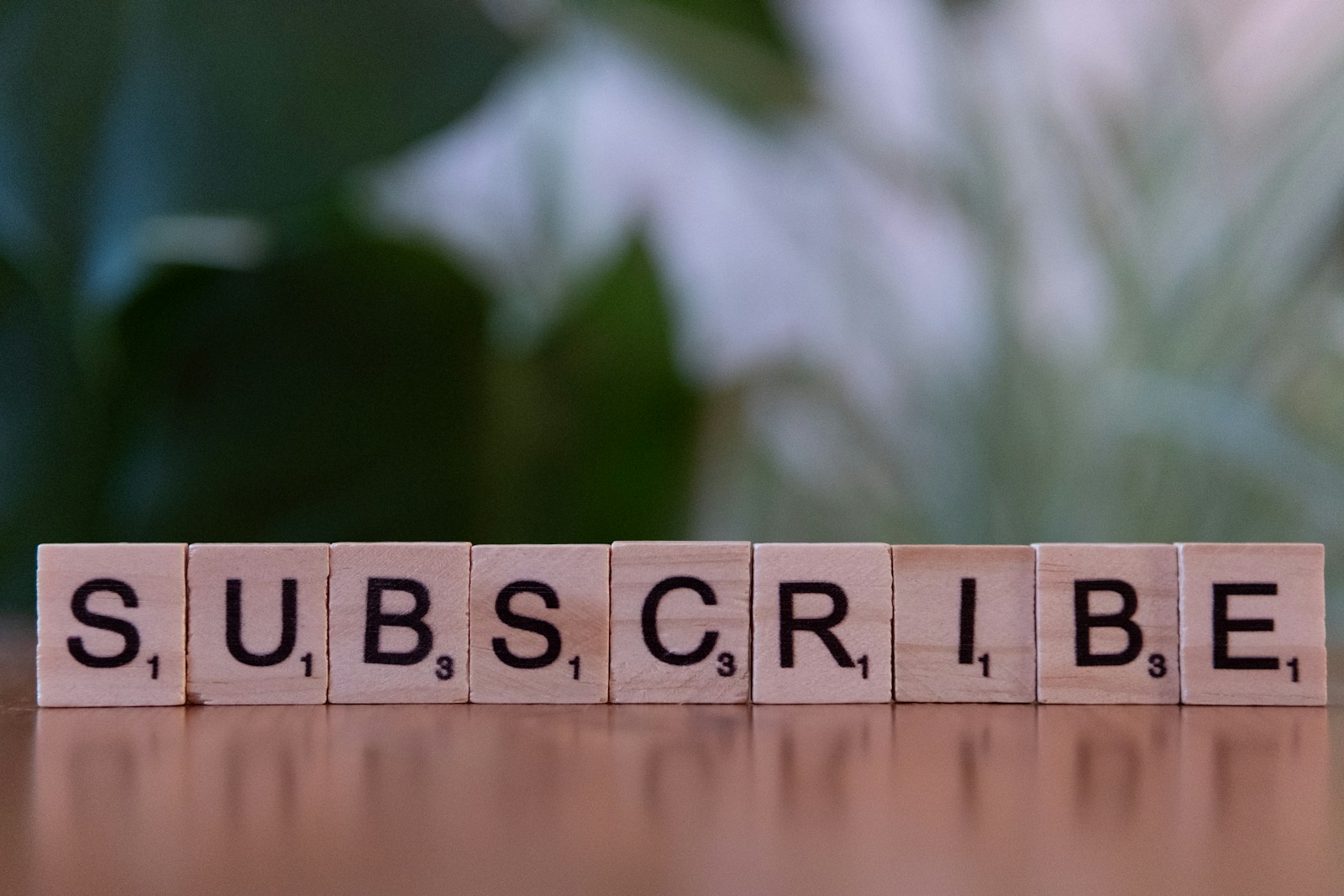 A wooden block spelling subscribe on a table