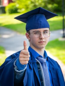 a man in a graduation gown giving a thumbs up